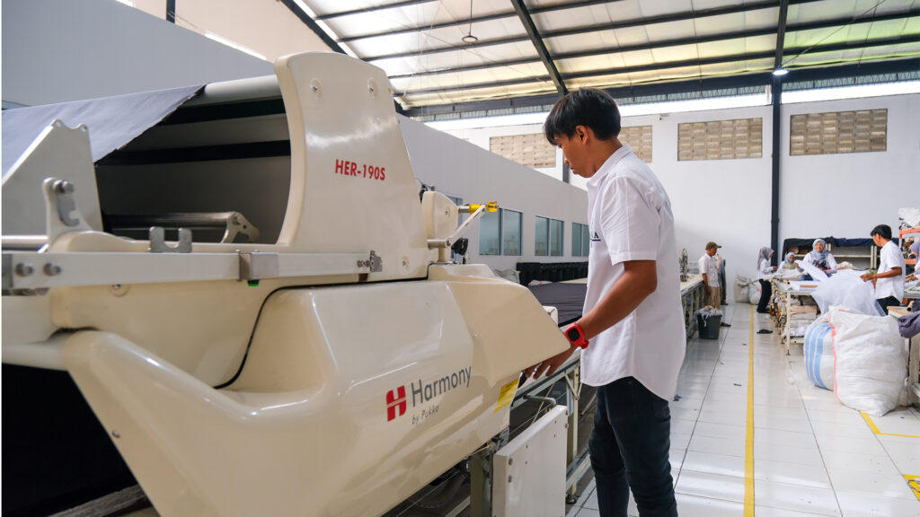 Tahap spreading dan cutting membagi gulungan kain menjadi panel-panel presisi yang siap untuk dirakit di lini jahit.